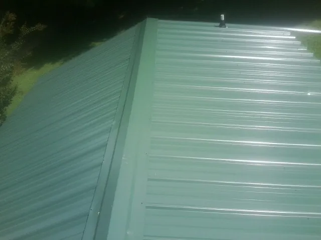 New green metal panels meeting at the ridge of a roof — Flat Roof Repair work by our crew in Wurtsboro