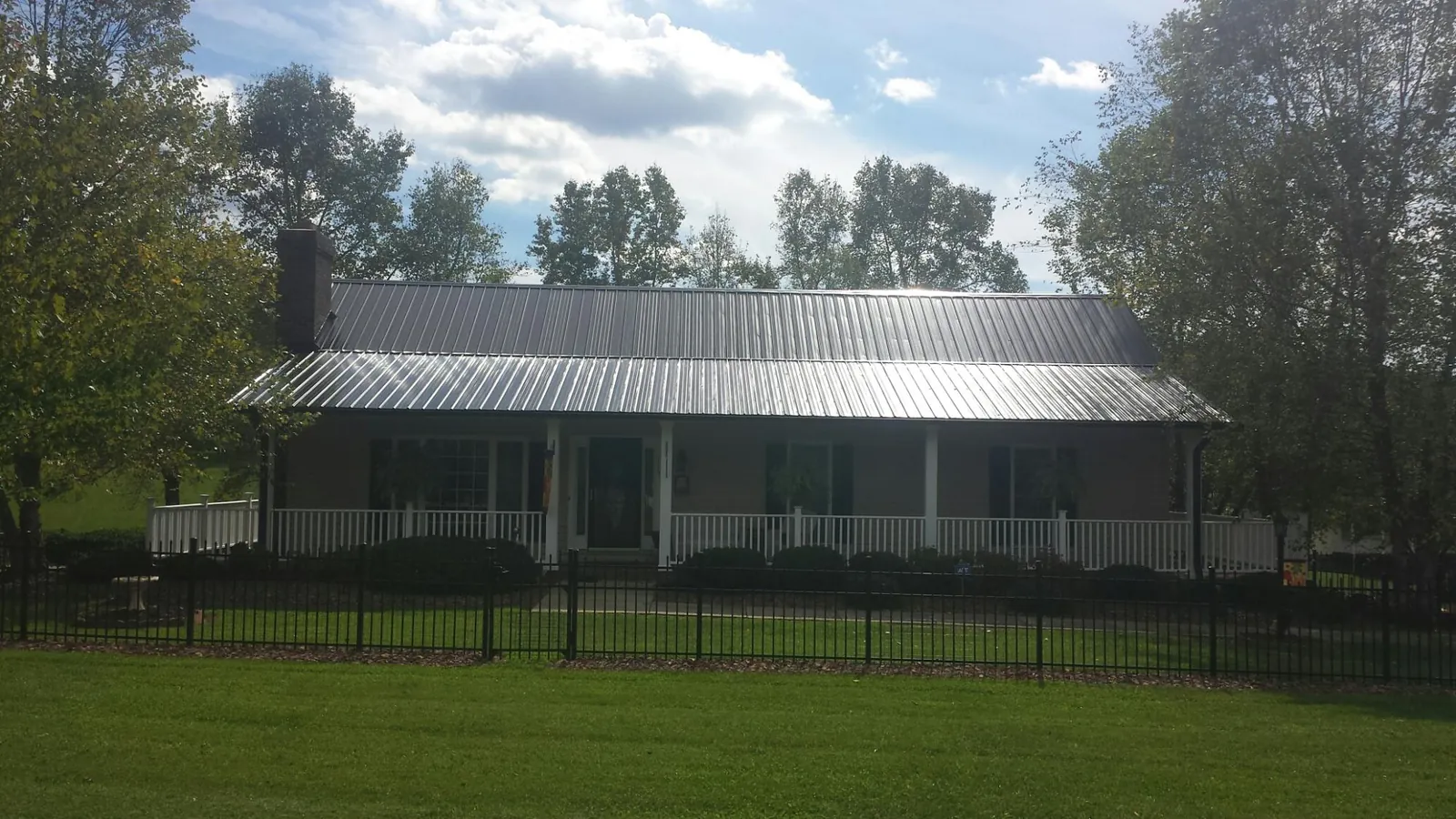 Gray metal roof on a brick ranch with a full width front porch — Gutter Guard Installation work by our crew in Wurtsboro
