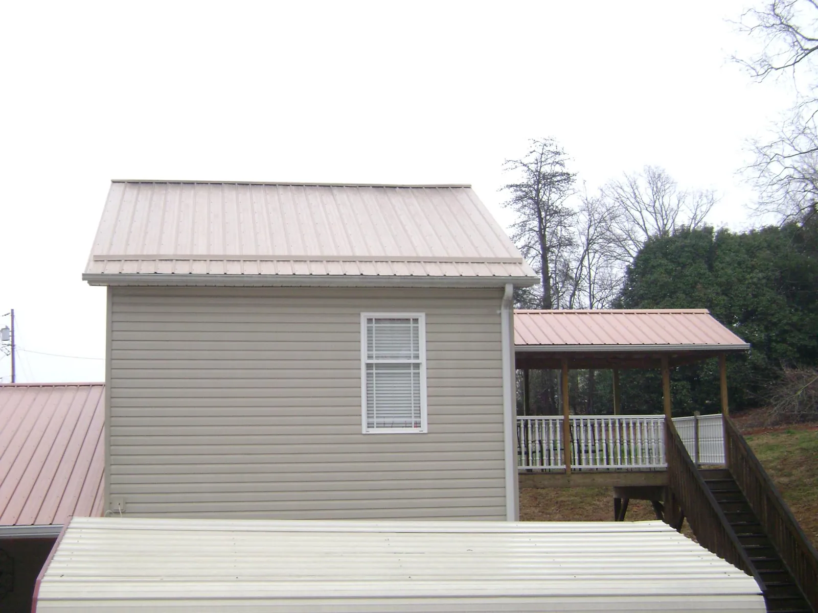Tan metal roofs on a two story addition and attached porch, from a Roof Replacement job in Wurtsboro
