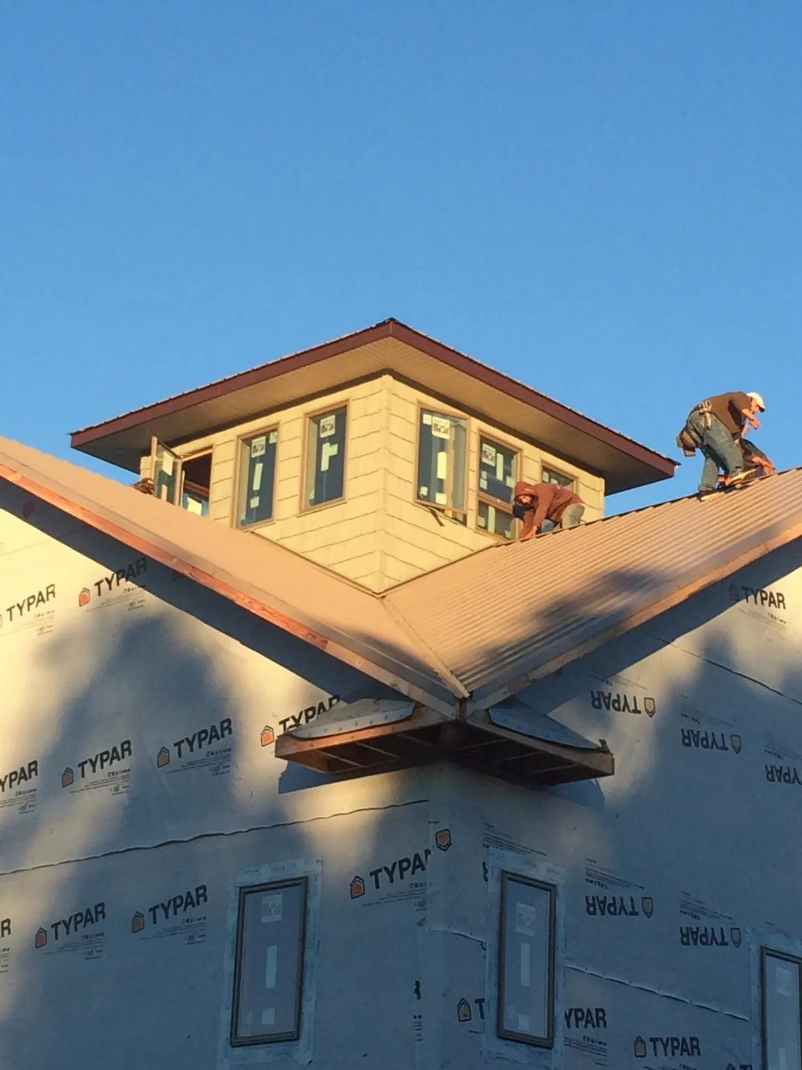 Roofers working around a rooftop cupola on a new metal roof at sunset — Roof Waterproofing in Wurtsboro by Roofing Brothers